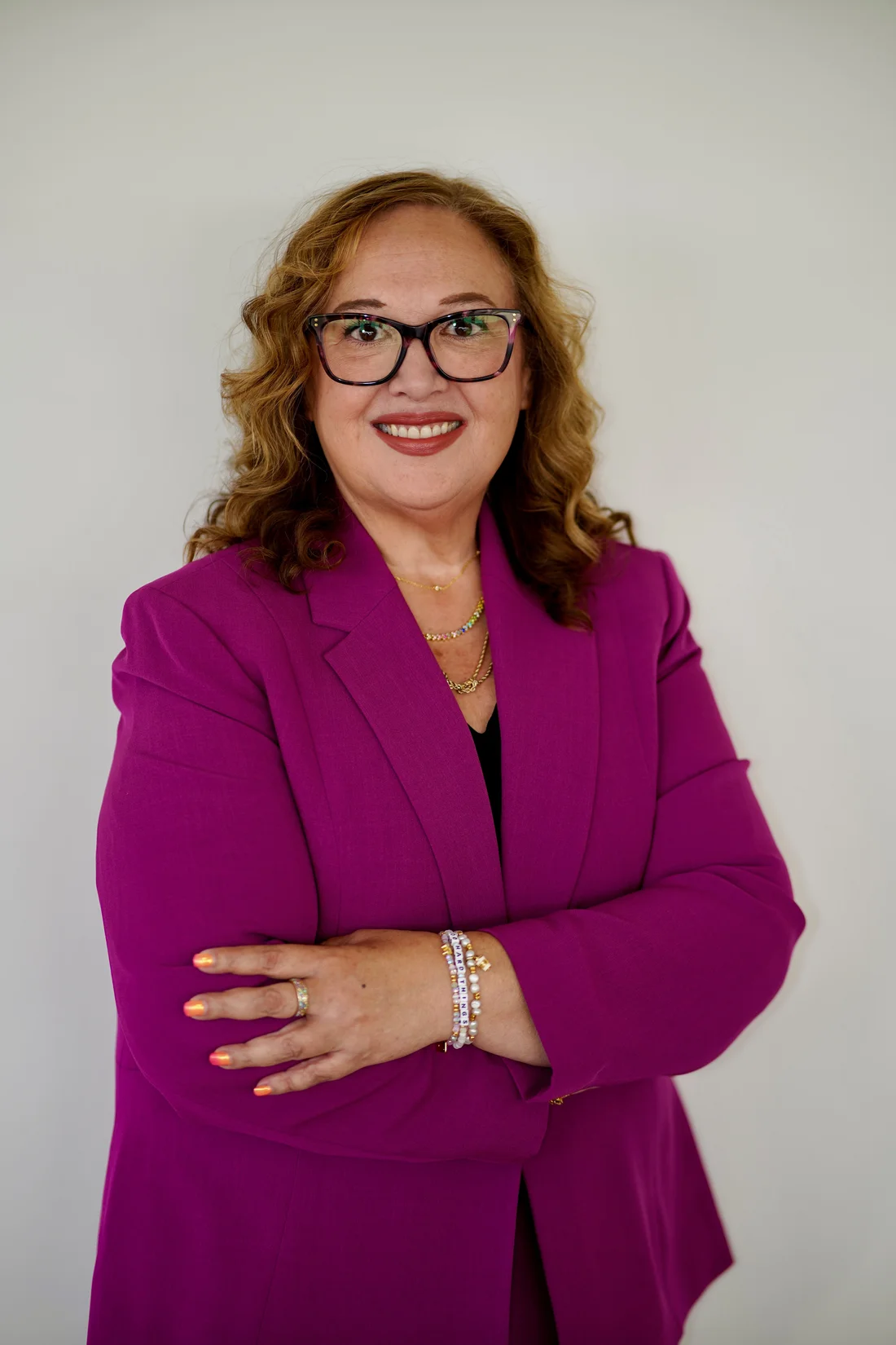 Jessica Hernandez with arms crossed in a magenta suit